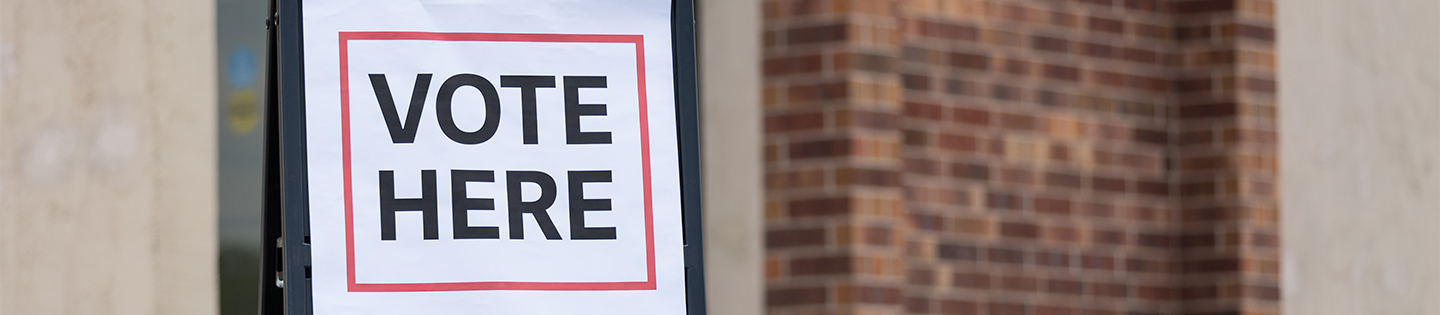 Vote Here sign in front of brick building