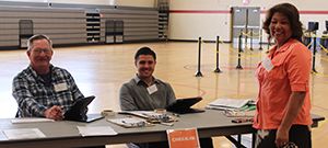 Three smiling election judges at a table in a gym