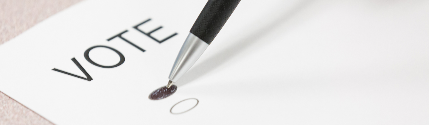 Pen filling in a small oval on a piece of paper with the word 'Vote' at the top