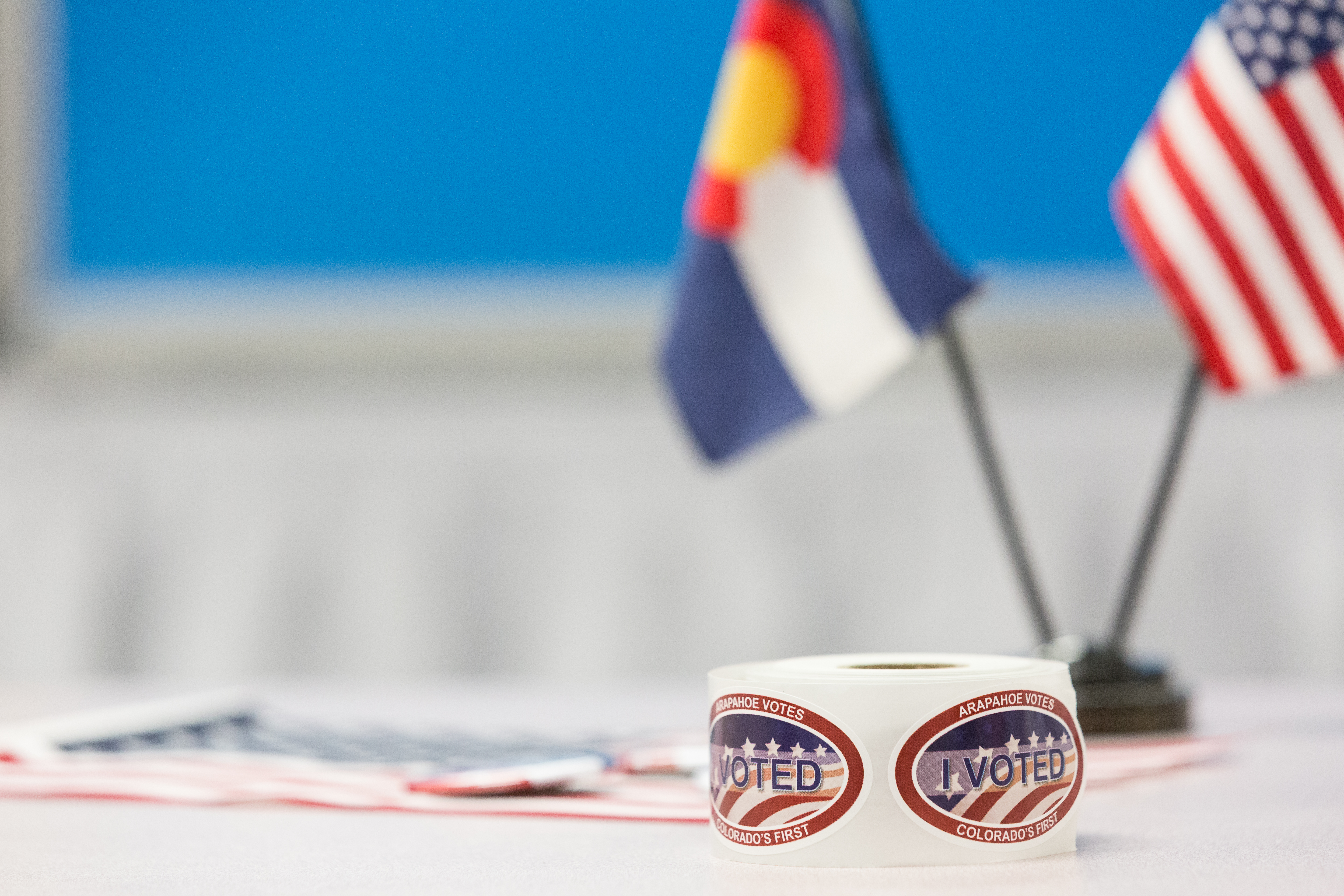 I Voted Stickers on desk with U.S. Flag and Colorado Flag