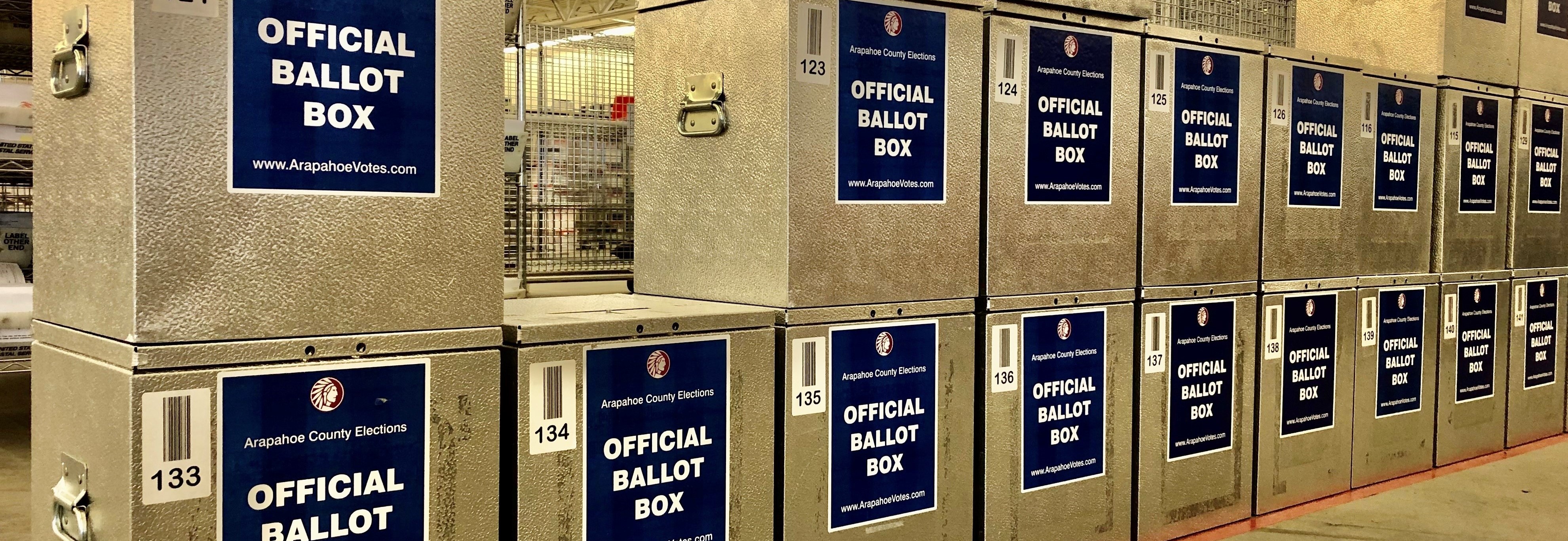 Line of 2 high silver ballot boxes stacked on floor