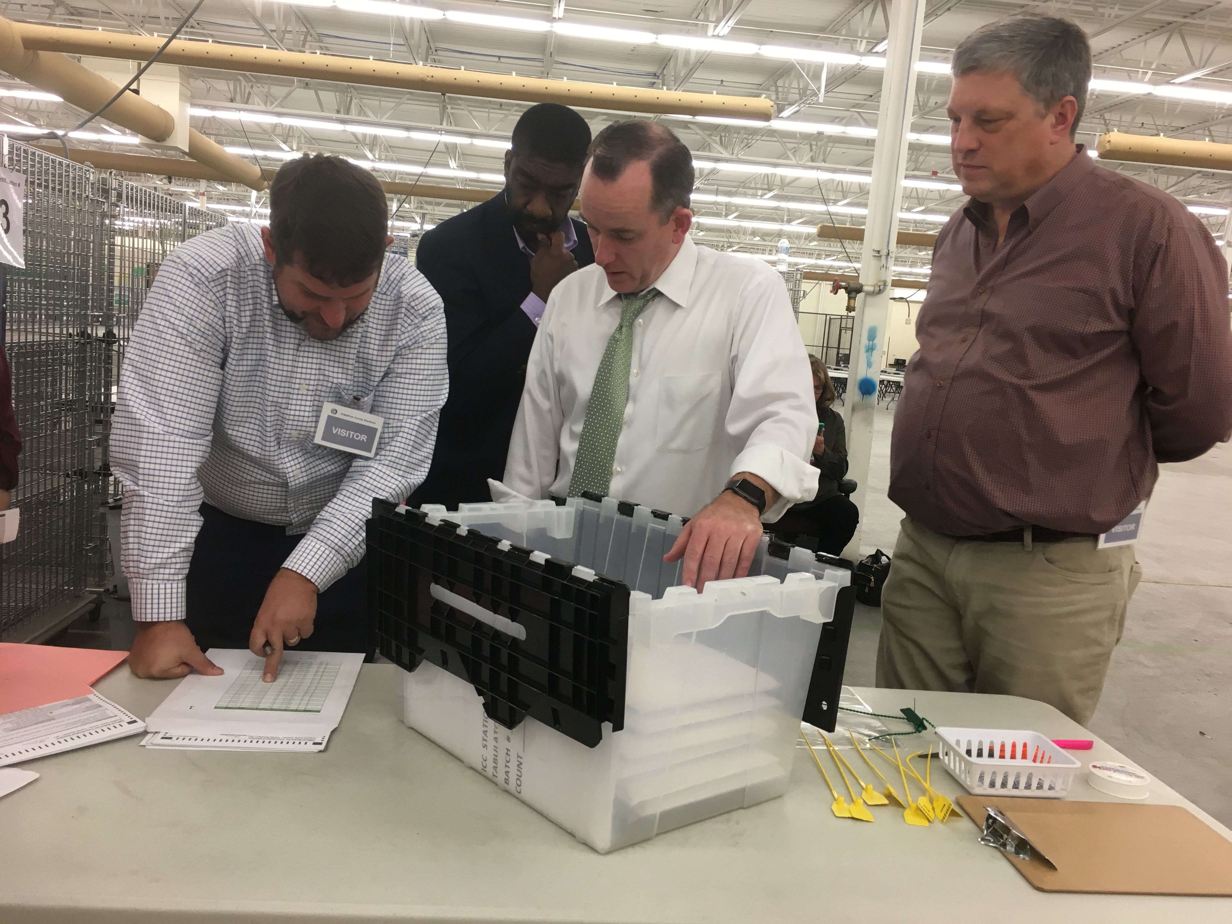 Four men stand at a table reviewing ballots in the Arapahoe County 2017 Risk Limiting Audit.