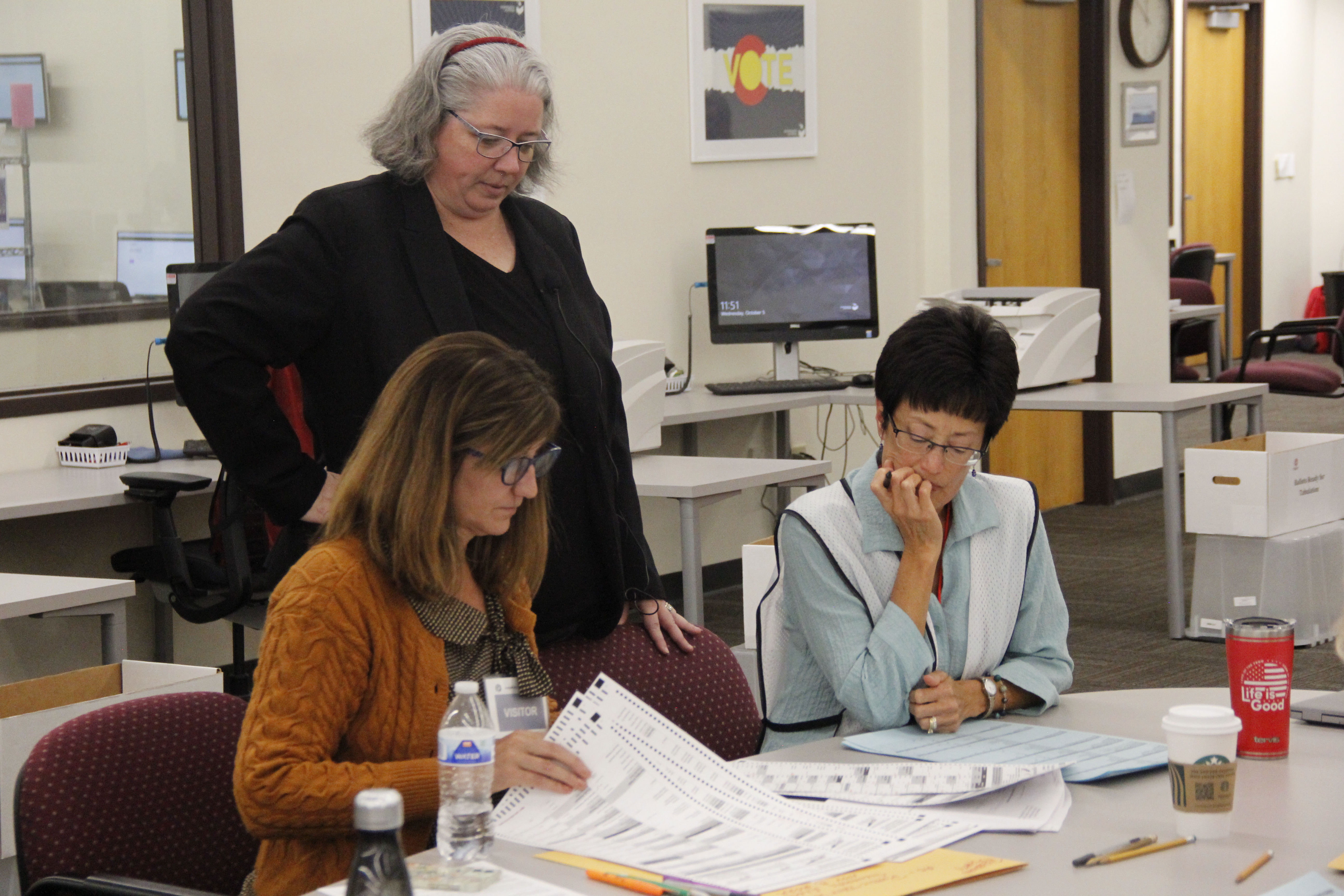 Depurty Dir. of Elections Peg Perl looks on as testing board members inspect test ballots for the 2022 LAT.