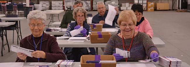 Bi partisan teams of two, open envelopes and remove ballots