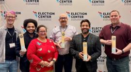 Elections administrators from Arapahoe, Denver and Adams counties pose for a photo holding award plaques